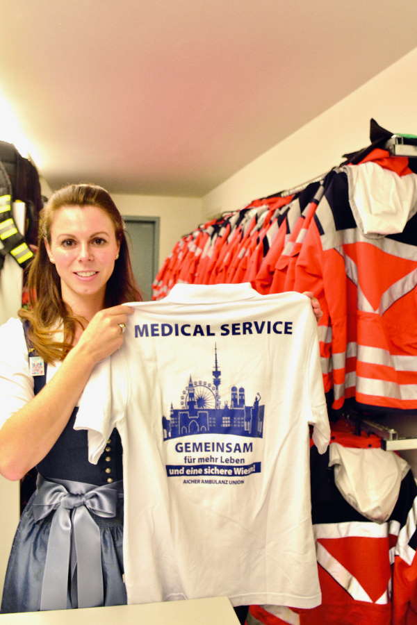Ulrike Krivec, Pressesprecherin der Aicher Ambulanz, zeigt die Shirts, die zur Ausstattung der Einsatzkräfte auf dem Wiesn-Gelände gehören. (Foto: Robert Auerbacher)